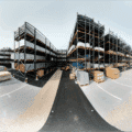 Vue d’un entrepôt de stockage extérieur avec rayonnages cantilever et racks à palettes en acier galvanisé, installés sur un sol stabilisé, accueillant des matériaux de construction et des marchandises palettisées, avec signalétique visible et zones de circulation pour engins de manutention – solution logistique durable et stratégique adaptée aux secteurs industriels comme la métallurgie, le bâtiment ou la sidérurgie.