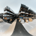 Vue d’un entrepôt de stockage extérieur avec rayonnages cantilever et racks à palettes en acier galvanisé, installés sur un sol stabilisé, accueillant des matériaux de construction et des marchandises palettisées, avec signalétique visible et zones de circulation pour engins de manutention – solution logistique durable et stratégique adaptée aux secteurs industriels comme la métallurgie, le bâtiment ou la sidérurgie.